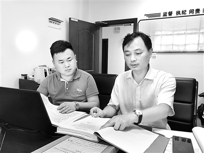 圖為肖鷹（右）正在查閱相關案件資料。